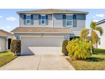 Two-story house with gray siding, white garage door, and landscaping at 361 Preserve Pointe Blvd, Davenport, FL 33837