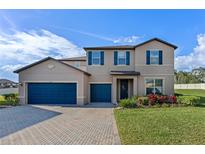 Charming two-story home with a three-car garage, brick driveway, well-manicured lawn, and colorful landscaping at 552 Keyhold Loop, Apopka, FL 32712