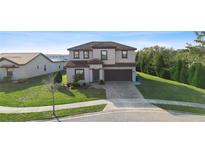 Two-story house with a brown roof, gray siding, and a brick paved driveway at 175 Claffey Ct, Haines City, FL 33844