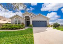 Charming single-story home featuring a blue garage door, arched entry, and lush landscaping at 2551 Bear Creek Ct, Kissimmee, FL 34747