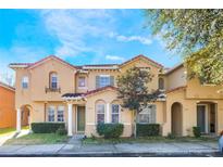 Tan two-story townhome with green door, and landscaped front yard at 2605 Andros Ln, Kissimmee, FL 34747