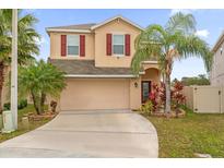 Two-story house with a beige exterior, red shutters, and a two-car garage at 3175 Turret Dr, Kissimmee, FL 34743