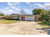 Traditional home featuring a brick facade, two-car garage, and meticulously kept lawn at 927 Buena Vista Ct, Orlando, FL 32818
