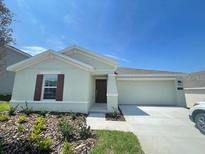 One-story home with light green exterior, landscaping, and attached garage at 1148 Pomelo St, Davenport, FL 33837