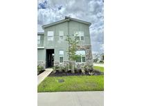 Modern two-story home with stone accents, green facade, and well-maintained landscaping at 1700 Tropical Palms Cir, Kissimmee, FL 34747