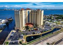 Aerial view of a luxury waterfront condo building with parking and a pond at 2801 S Ridgewood Ave # 807, South Daytona, FL 32119