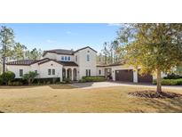 Two-story house with tile roof, large windows, and a three-car garage at 506 Yellow Submarine Ct, Groveland, FL 34737