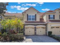 Charming townhome with a red tile roof, stone accents, and two-car garage at 7189 Regina Way, Orlando, FL 32819