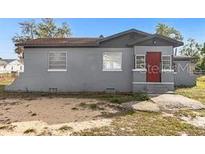 Single story home with grey exterior paint, a red front door and minimal landscaping at 131 W Crystal Ave, Lake Wales, FL 33853