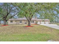Single-story home with stone accents, mature trees, and a three-car garage at 2770 Windsong Ln, St Cloud, FL 34772