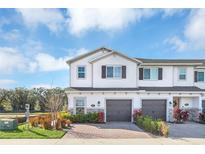 Two-story townhome with gray garage doors and landscaping at 4298 Campsite Loop, Orlando, FL 32824
