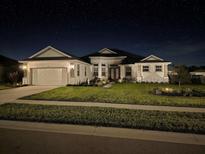 Charming single-Gathering home showcasing well-manicured lawn, neutral paint, two-car garage, and inviting entrance at night at 530 Sanctuary Blvd, Winter Haven, FL 33881