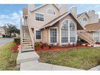 Tan two-story condo with a staircase, landscaping, and a large window at 625 Greencove Ter # 123, Altamonte Springs, FL 32714