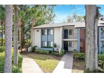 Inviting two-story condo building with lush landscaping, sidewalk, and fresh, light-blue and white paint at 14 Escondido Cir # 129, Altamonte Springs, FL 32701