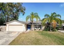 Charming single-story home featuring a well-maintained lawn, palm trees, and a vibrant blue front door at 145 Roosevelt Pl, Maitland, FL 32751