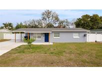 Charming one-story home with covered parking, a blue front door, and a well-manicured lawn at 3311 Sutton Dr, Orlando, FL 32810