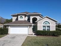 Charming two-story home featuring a manicured lawn and an attached two-car garage at 8130 Yellow Crane Dr, Kissimmee, FL 34747