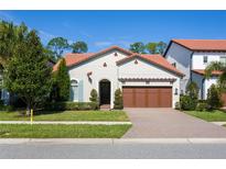 Charming single-Gathering home featuring a tile roof, manicured lawn, and a brick-paved driveway leading to a two-car garage at 10420 Royal Cypress Way, Orlando, FL 32836
