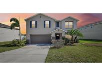 Two-story home featuring a two-car garage, well-manicured lawn, and mature trees at 11434 Wishing Well Ln, Clermont, FL 34711