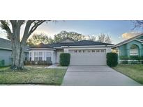 Charming single-story home featuring an attached two-car garage and mature landscaping at 14424 Quail Trail Ct, Orlando, FL 32837