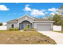Gray house with a two-car garage and landscaped front yard at 2011 Begonia Way, Poinciana, FL 34759