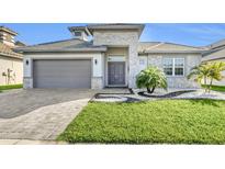 Beautiful single-Gathering home with a manicured lawn and a gray stone exterior and matching garage door at 247 Hampton Loop, Davenport, FL 33837
