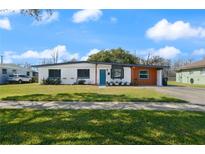 Charming single-story home boasts a well-manicured lawn, inviting blue door, and covered parking at 608 S Oxalis Ave, Orlando, FL 32807