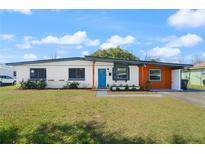 Charming single-story home featuring a vibrant blue front door, well-maintained lawn and tidy landscaping at 608 S Oxalis Ave, Orlando, FL 32807