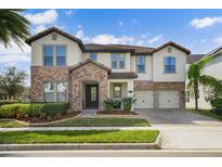 Beautiful two-story home featuring a combination of stone and stucco, a tile roof, and a well-manicured lawn at 13596 Gorgona Isle Dr, Windermere, FL 34786