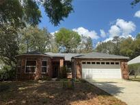 Charming single-story brick home with a two-car garage, well-maintained landscaping, and mature shade trees at 2047 Friar Tuck Ln, Orange City, FL 32763