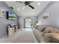 Comfortable living room with neutral walls, tile flooring, and sliding glass doors to the outside at 2214 Se Sawgrass Ct, Winter Haven, FL 33884
