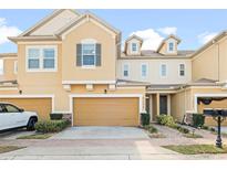 Charming townhome with tan exterior, well-maintained landscaping, and private two-car garage at 17438 Promenade Dr, Clermont, FL 34711