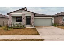 Inviting single-Gathering home showcasing stone accents, a two-car garage, and well-maintained landscaping at 1893 Sierra Sun Way, Clermont, FL 34715