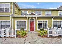 Inviting townhome with charming curb appeal, featuring a red front door and a well-maintained white picket fence at 4004 Santa Maria Dr # 105, Kissimmee, FL 34741