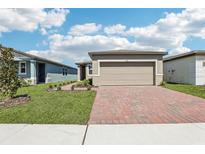 Charming single-Gathering home featuring a brick driveway, two car garage and manicured lawn at 4031 Cooperleaf Ln, Poinciana, FL 34759