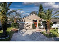 Charming single-story home featuring a well-manicured lawn, a bright orange front door, and beautiful palm trees at 491 Goldenmoss Loop, Ocoee, FL 34761