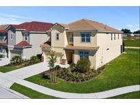 Two-story house with a tan exterior, landscaped lawn, and a two-car garage at 5414 Oakgrain Ct, Davenport, FL 33837