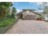 Charming home featuring a brick driveway, a two-car garage, and lush landscaping at 7943 Snowberry Cir, Orlando, FL 32819