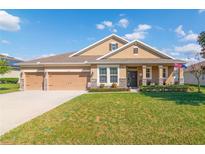 Charming one-story home with manicured lawn, three car garage and covered front porch with stone accents at 1161 Spinning Wheel Dr, Apopka, FL 32712