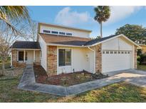 Exterior view of home featuring an attached two-car garage, stone accents, and manicured landscaping at 124 Loon Ct, Daytona Beach, FL 32119