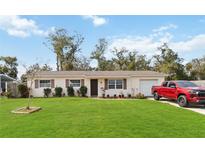 Charming single-story home featuring a well-manicured lawn, and a red truck parked in the driveway at 5326 Metro Dr, Orlando, FL 32818