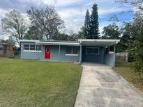 Charming single-story home features a red front door, carport, and well-maintained lawn at 158 Country Club Cir, Sanford, FL 32771