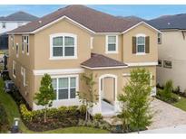 Two-story house with tan siding, dark roof, and landscaping at 1830 Sawyer Palm Pl, Kissimmee, FL 34747