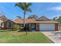 Charming brick home with a well-manicured lawn, palm tree and an attached two car garage at 1971 Urbana Ave, Deltona, FL 32725