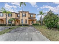 Charming townhome featuring a welcoming entrance, a neatly maintained lawn, and vibrant palm trees at 2153 Calabria Ave, Davenport, FL 33897