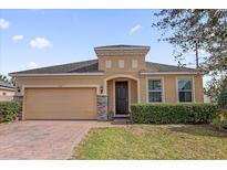 Charming single-story home with brick driveway, two-car garage, arched entryway, and manicured landscaping at 3337 Reedy Glen Dr, Kissimmee, FL 34758