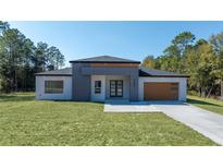 Contemporary single-story home featuring a modern gray and white facade and well-manicured lawn at 5544 Sw 136Th Ave, Ocala, FL 34481