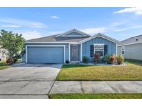 Charming single-story home with blue siding, manicured lawn, and attached two-car garage at 812 Gisele Ct, Haines City, FL 33844