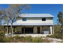 Two-story home with a metal roof and a covered porch, blending seamlessly with the surrounding natural landscape at 40200 Swift Rd, Eustis, FL 32736