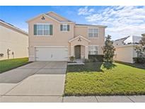 Charming two-story home with stucco exterior, attached garage, and well-maintained lawn on a sunny day at 817 Sheen Cir, Haines City, FL 33844